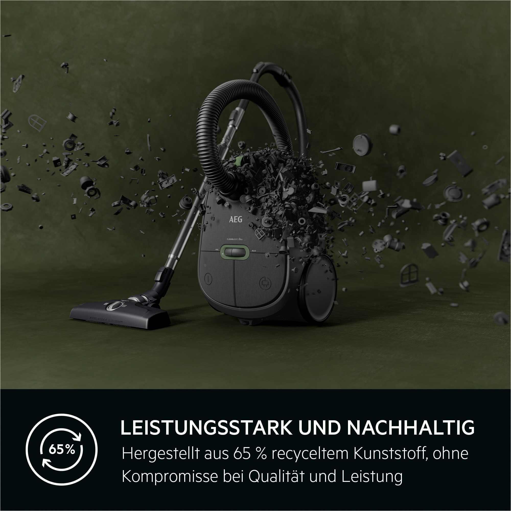 Ein Staubsauger mit dunklem Gehäuse und grünem Knopf. Der Hintergrund zeigt explodierende Trümmer.