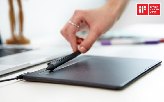 Une main tenant un stylo au-dessus d'une tablette graphique avec un logo de prix de design.