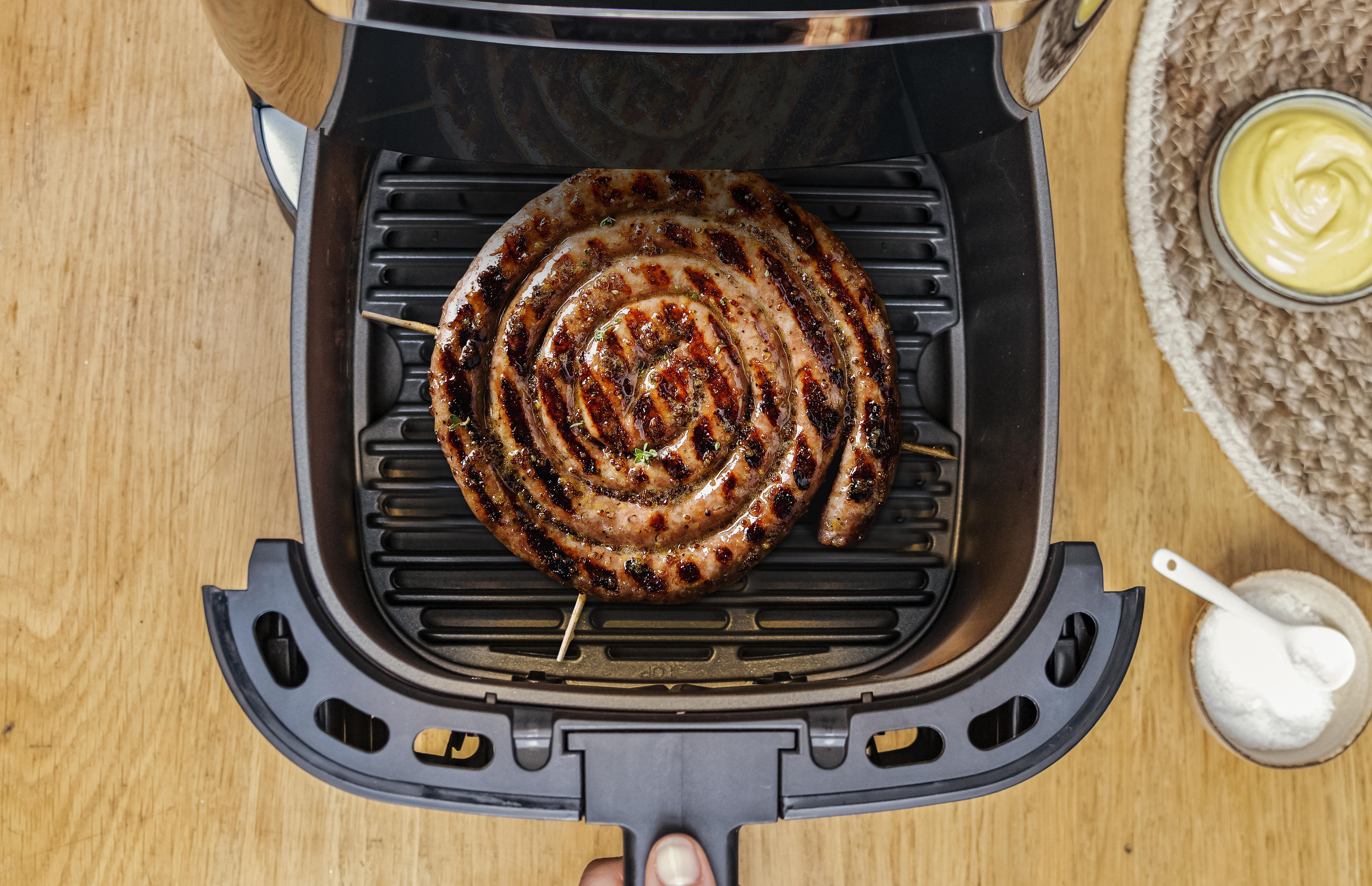 Eine Spiralwurst in einer Heißluftfritteuse mit Senf und Salz.