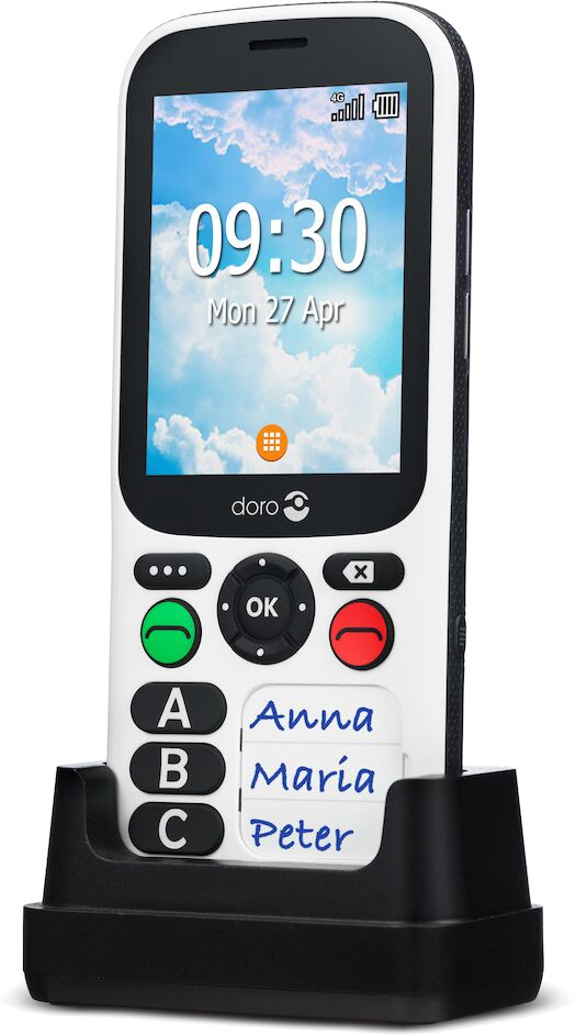 Téléphone Doro blanc avec de gros boutons et une station de charge. L'écran affiche l'heure et trois noms de contact.