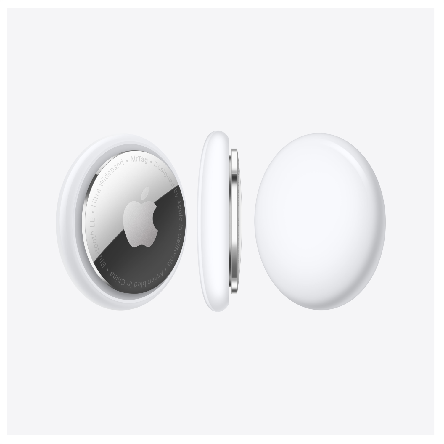 Drie witte Apple AirTags, één met het Apple-logo, tegen een grijze achtergrond, verschillende hoeken.