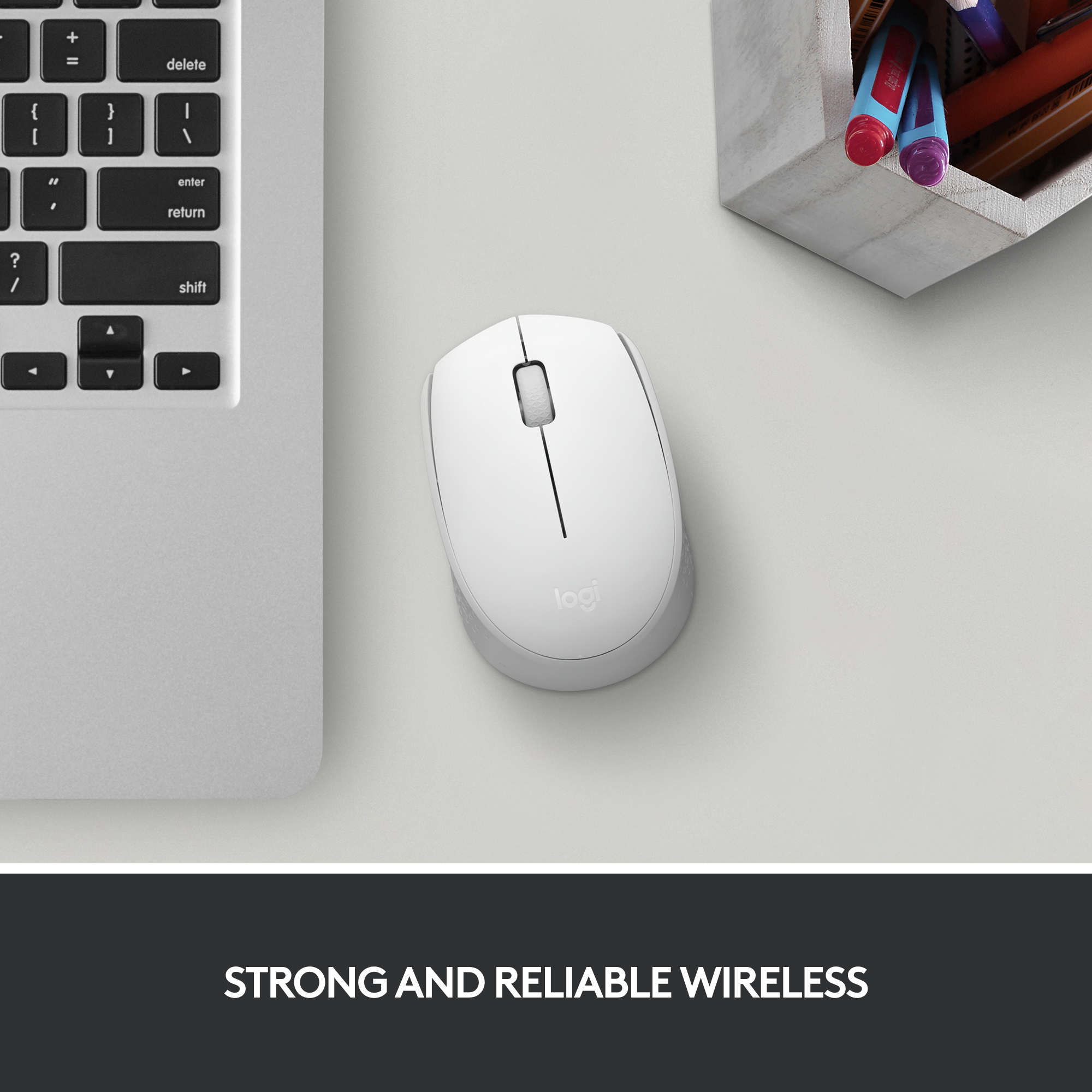 Weiße Computermaus auf einem Schreibtisch neben einem Laptop und einem Stifthalter.