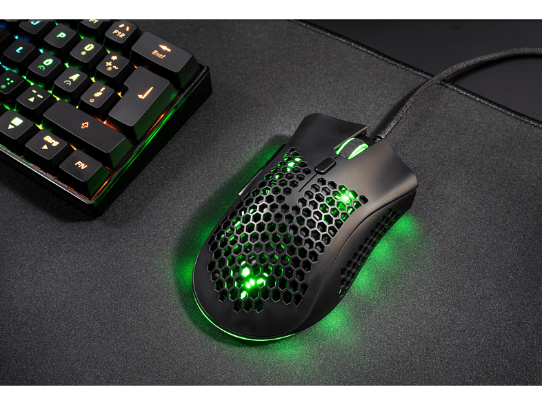 Un ratón para juegos negro con luces verdes y un teclado con luces en un escritorio negro. Enfoque en el ratón.
