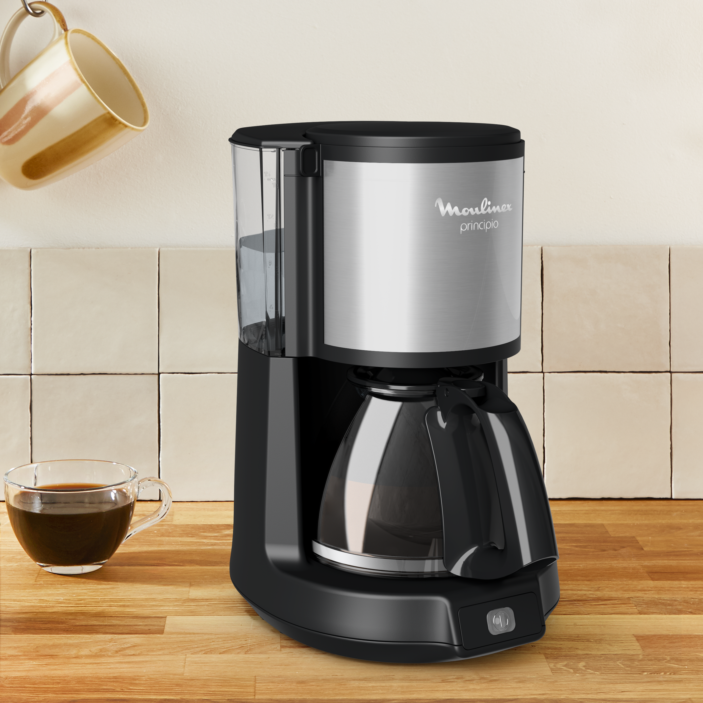 Cafetera negra y plateada sobre una superficie de madera. Taza y jarra cerca.
