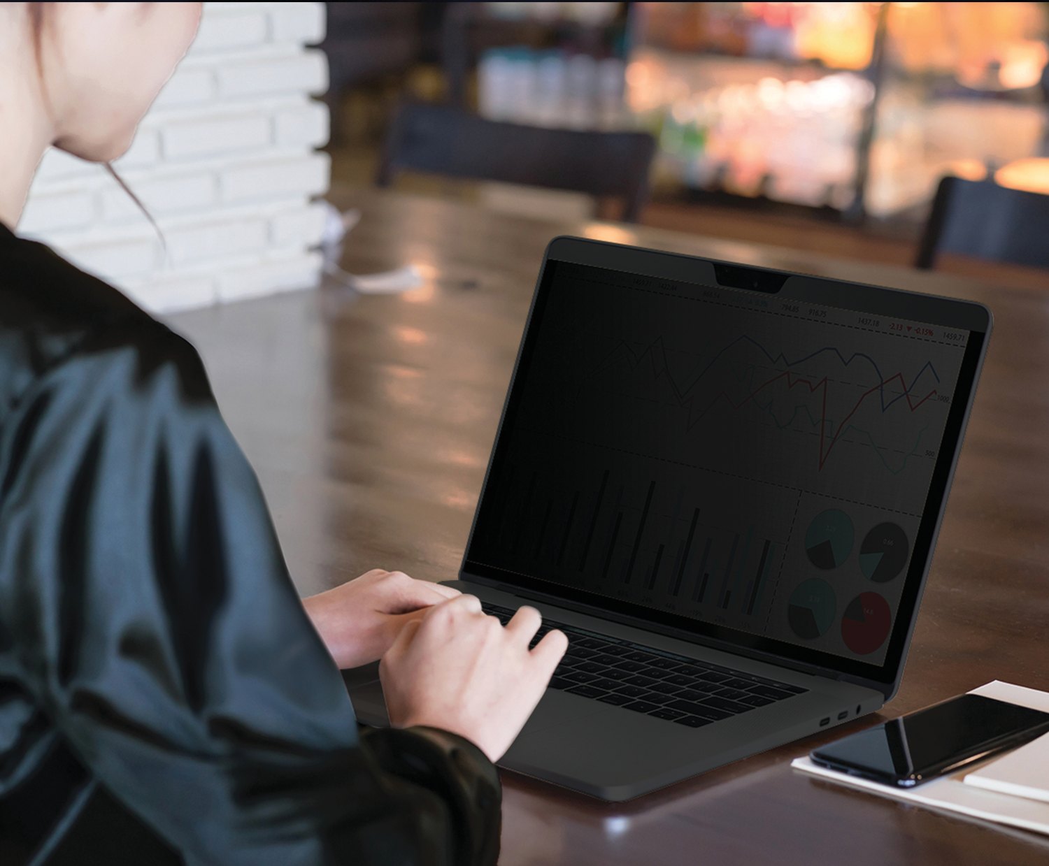 Egy nő laptopot használ adatvédelmi képernyővel az asztalon.