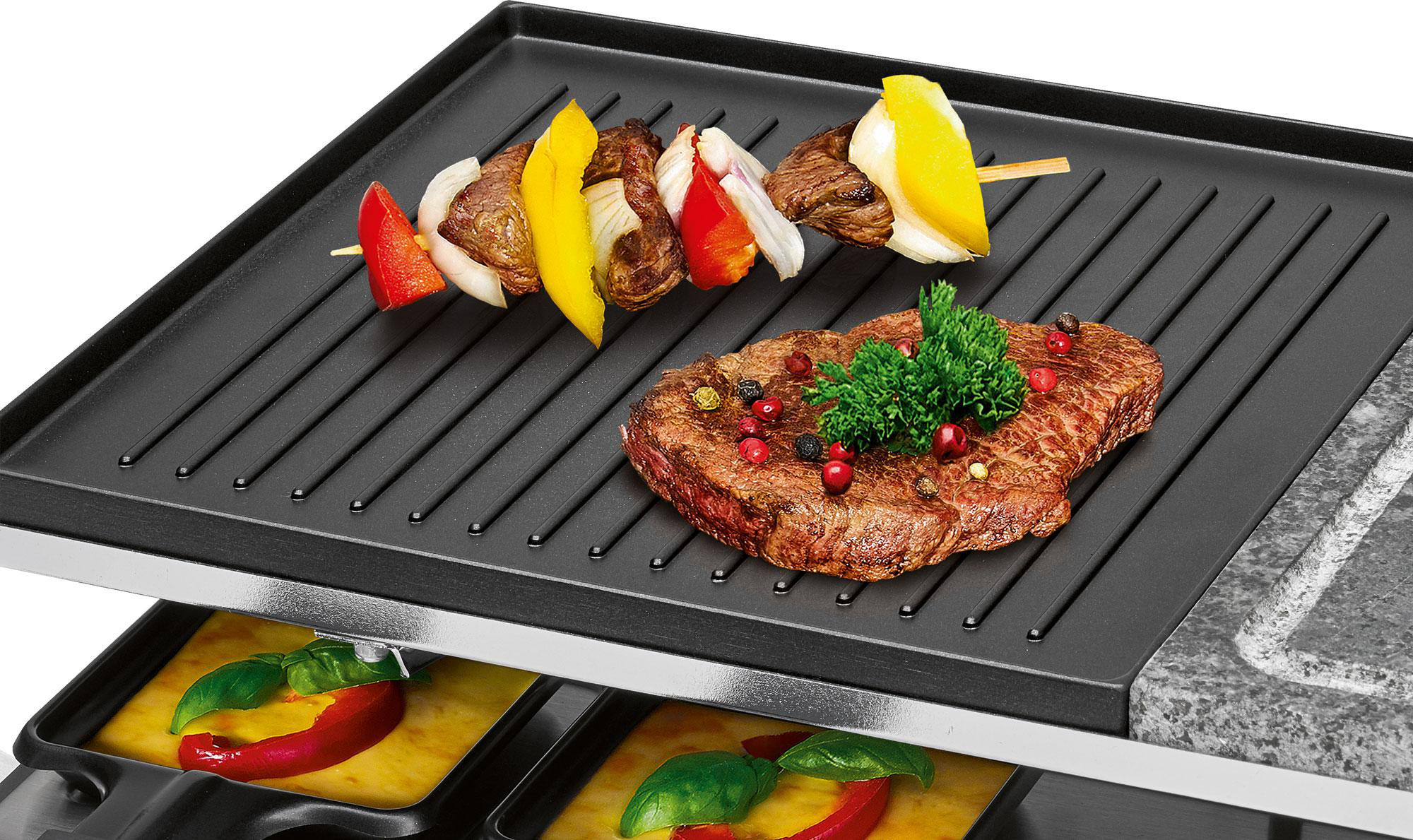 Ein Grill mit gebratenem Fleisch und einem Spieß mit Gemüse, servierfertig, auf schwarzer Oberfläche.