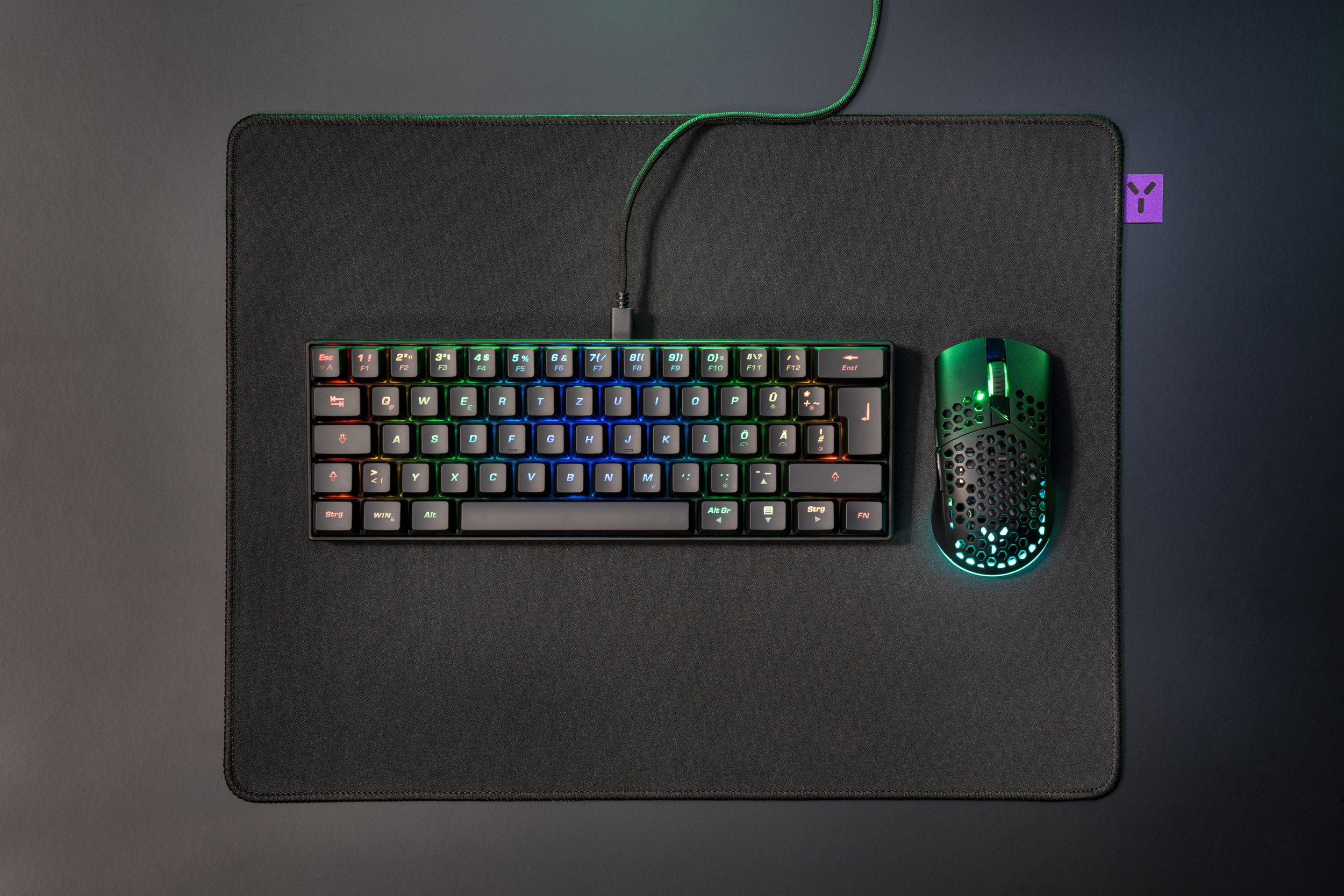 Clavier, souris et tapis. Clavier avec touches colorées. Souris verte. Fond gris foncé.