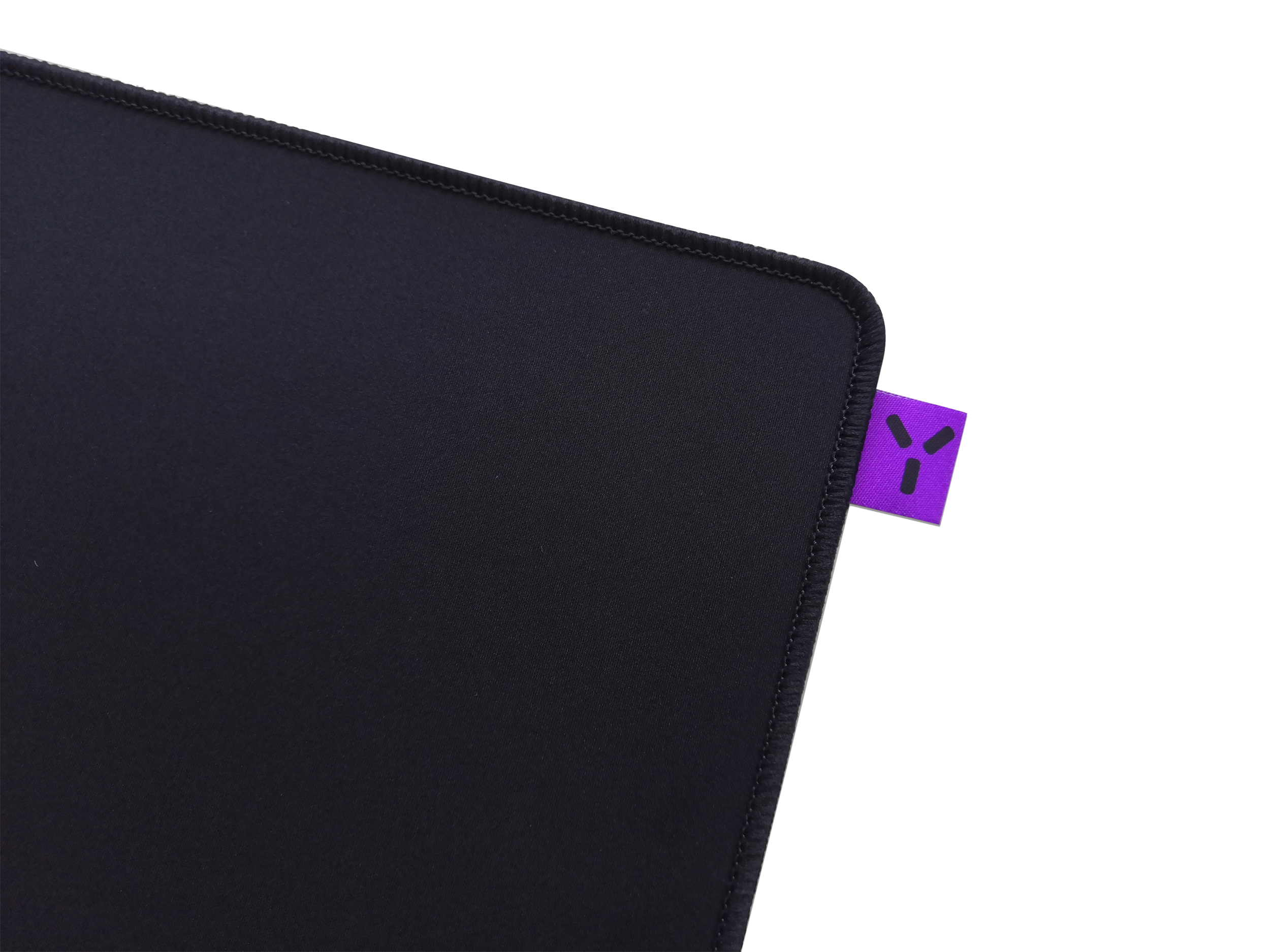 Tapis de souris de jeu noir avec une étiquette logo violette dans le coin droit.