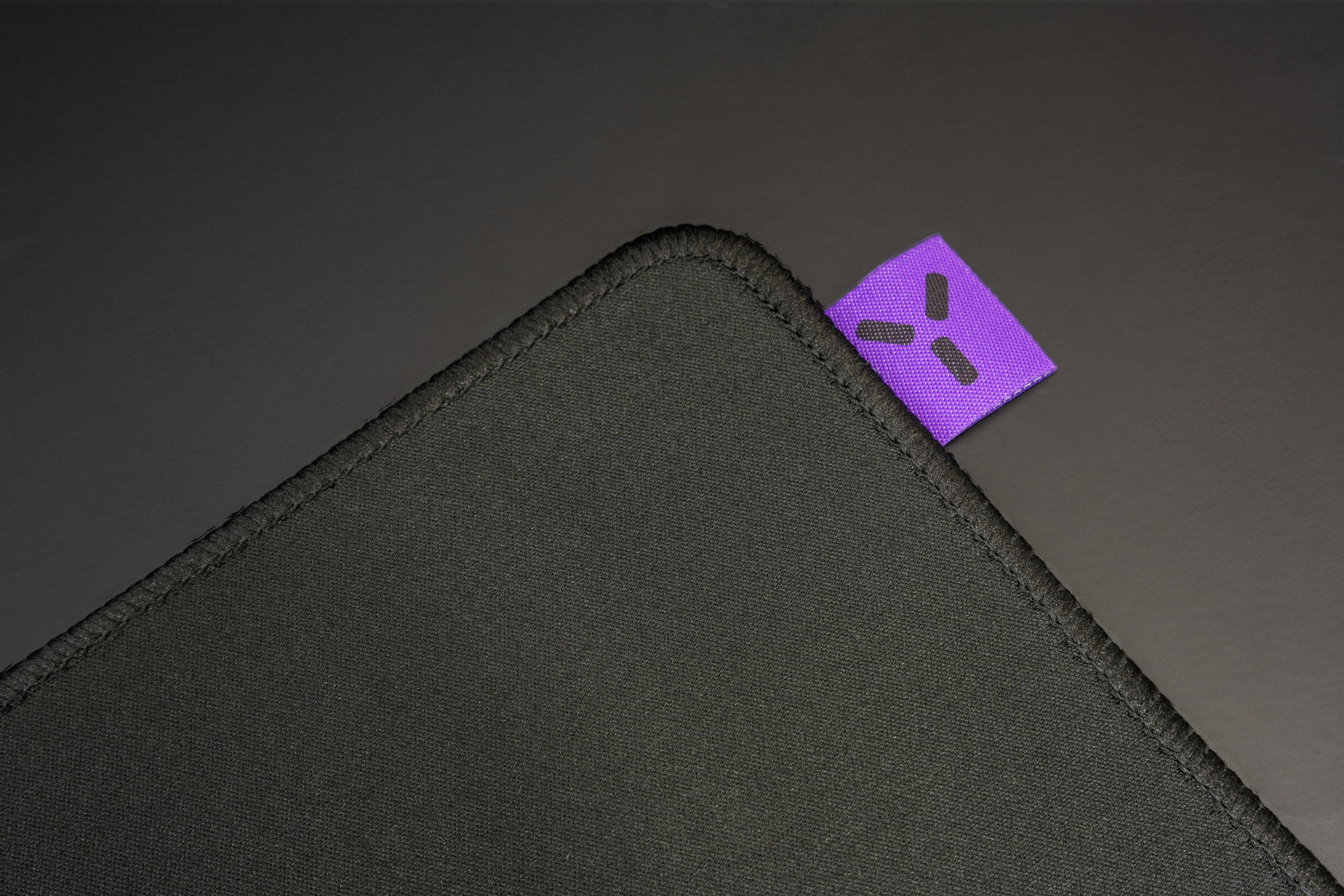 Tapis de souris noir, étiquette violette dans le coin, surface noire.