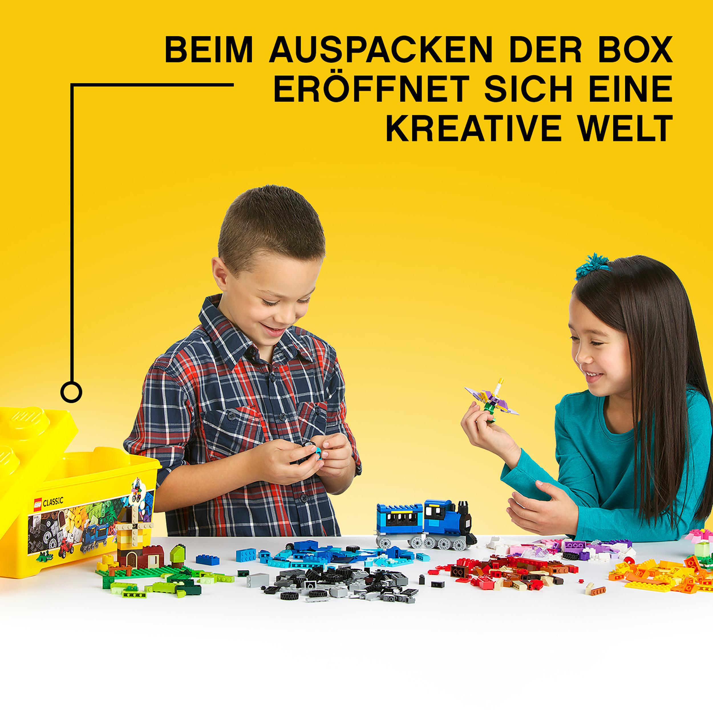 Zwei Kinder bauen mit Lego-Steinen, gelbe Lego-Box links.