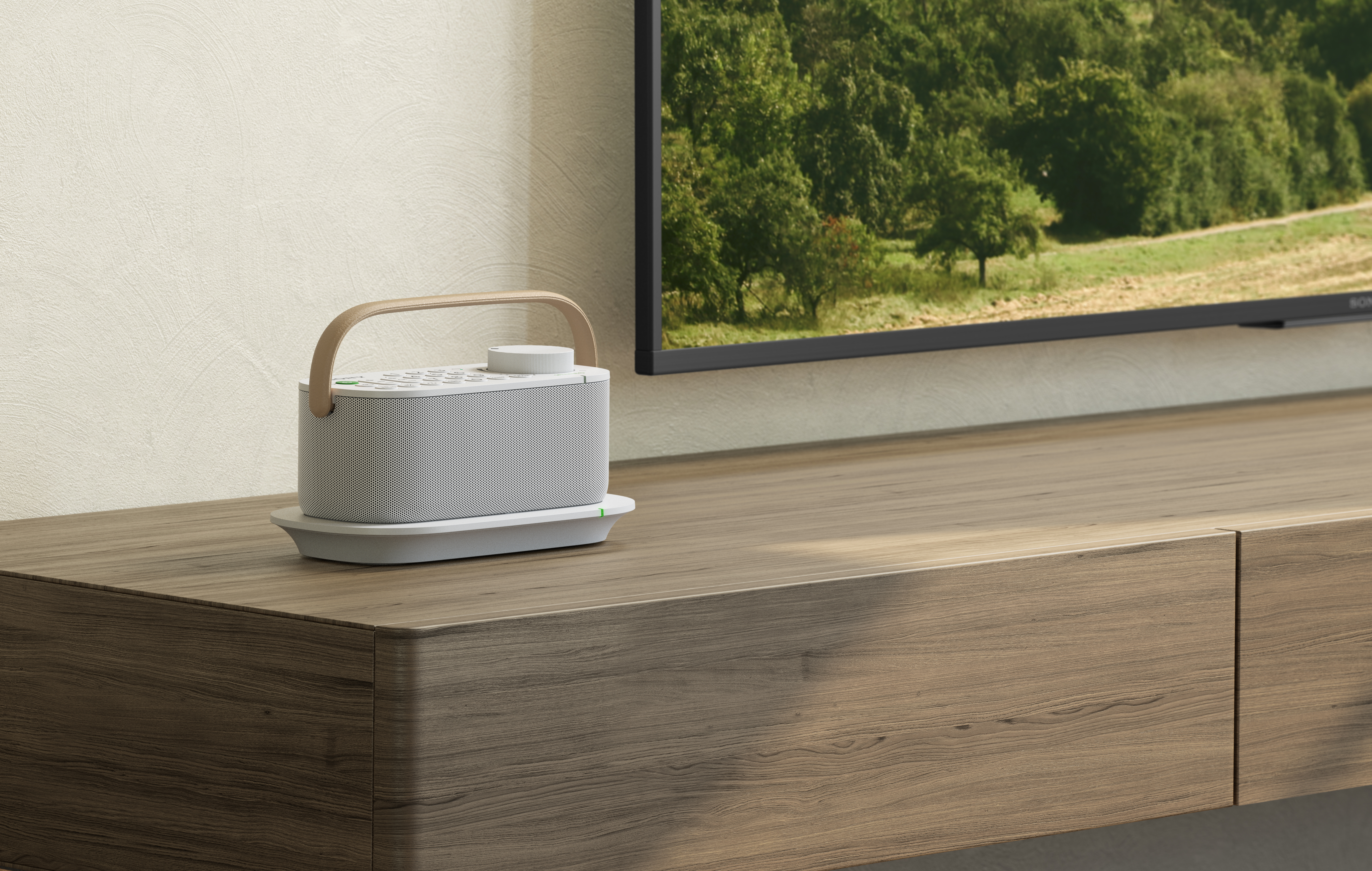 Un pequeño altavoz blanco con asa de madera, sobre una bandeja, cerca de un televisor.