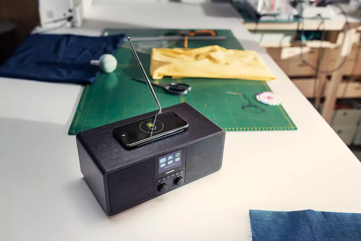 Radio noire avec téléphone en charge. Outils et tissu sur la table.
