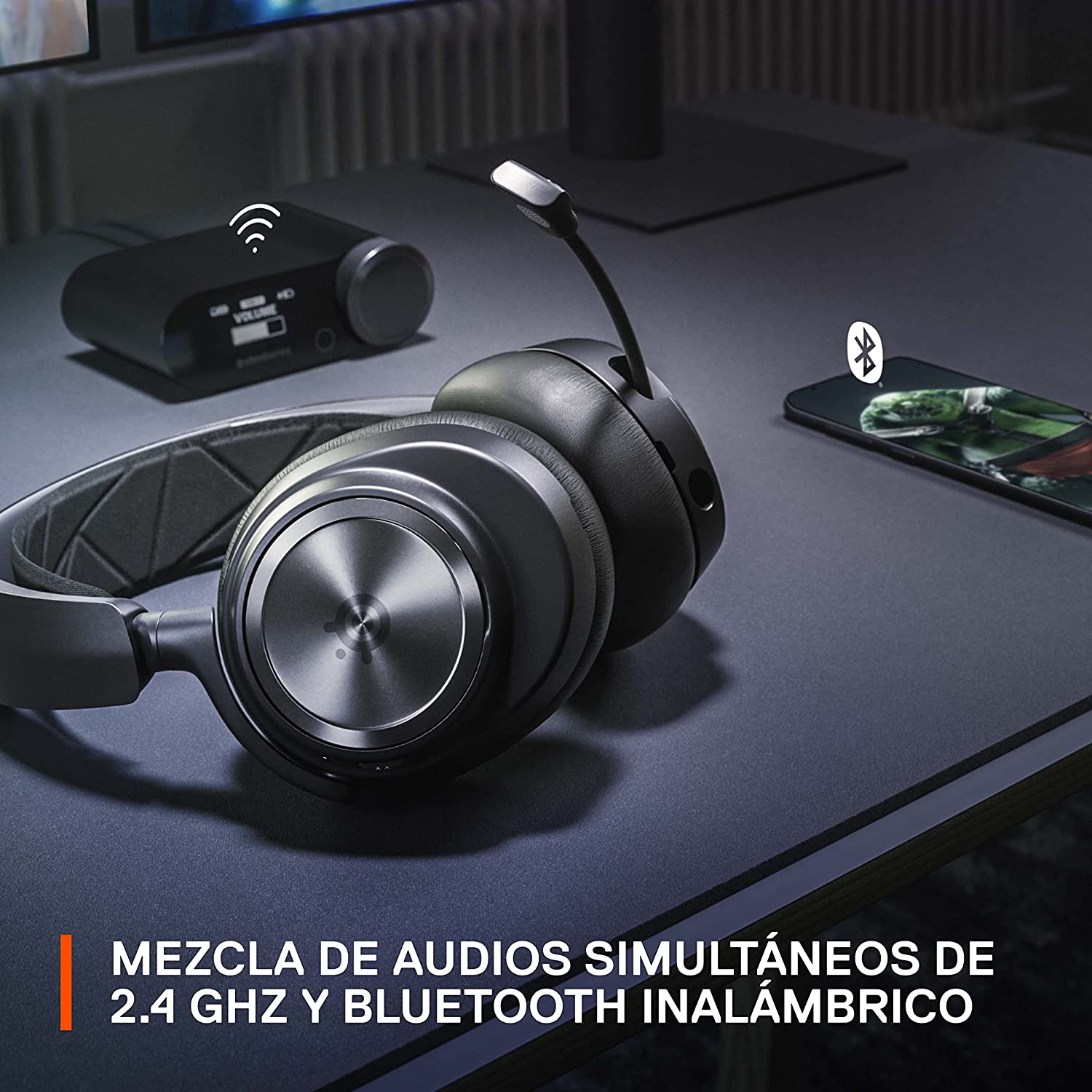 Auriculares inalámbricos negros con micrófono. Hay un pequeño dispositivo en el escritorio.