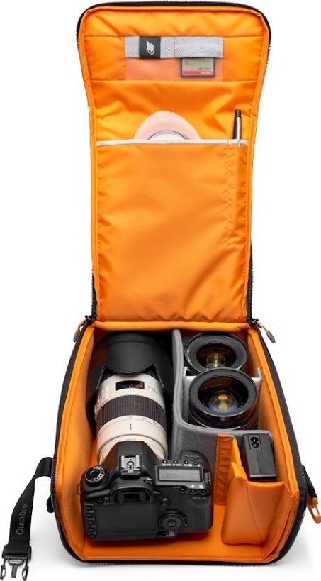 Sac photo ouvert avec appareil photo, objectifs et accessoires. Intérieur orange, extérieur noir. Divers articles sont visibles.