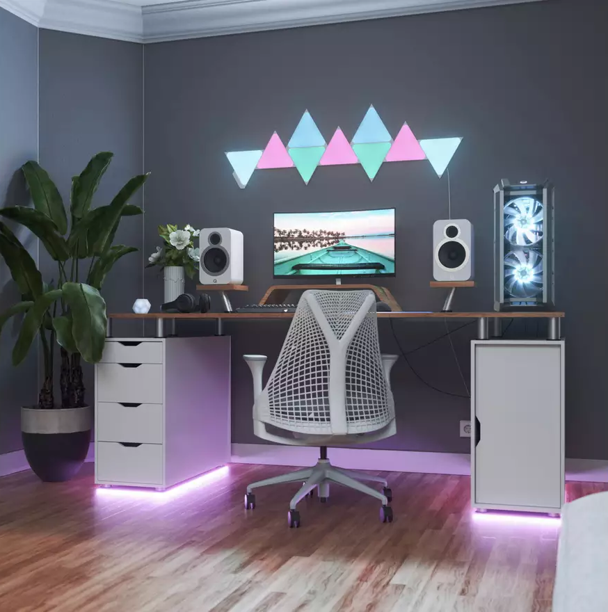 Un setup home office con computer, due altoparlanti, sedia da gaming e luci.