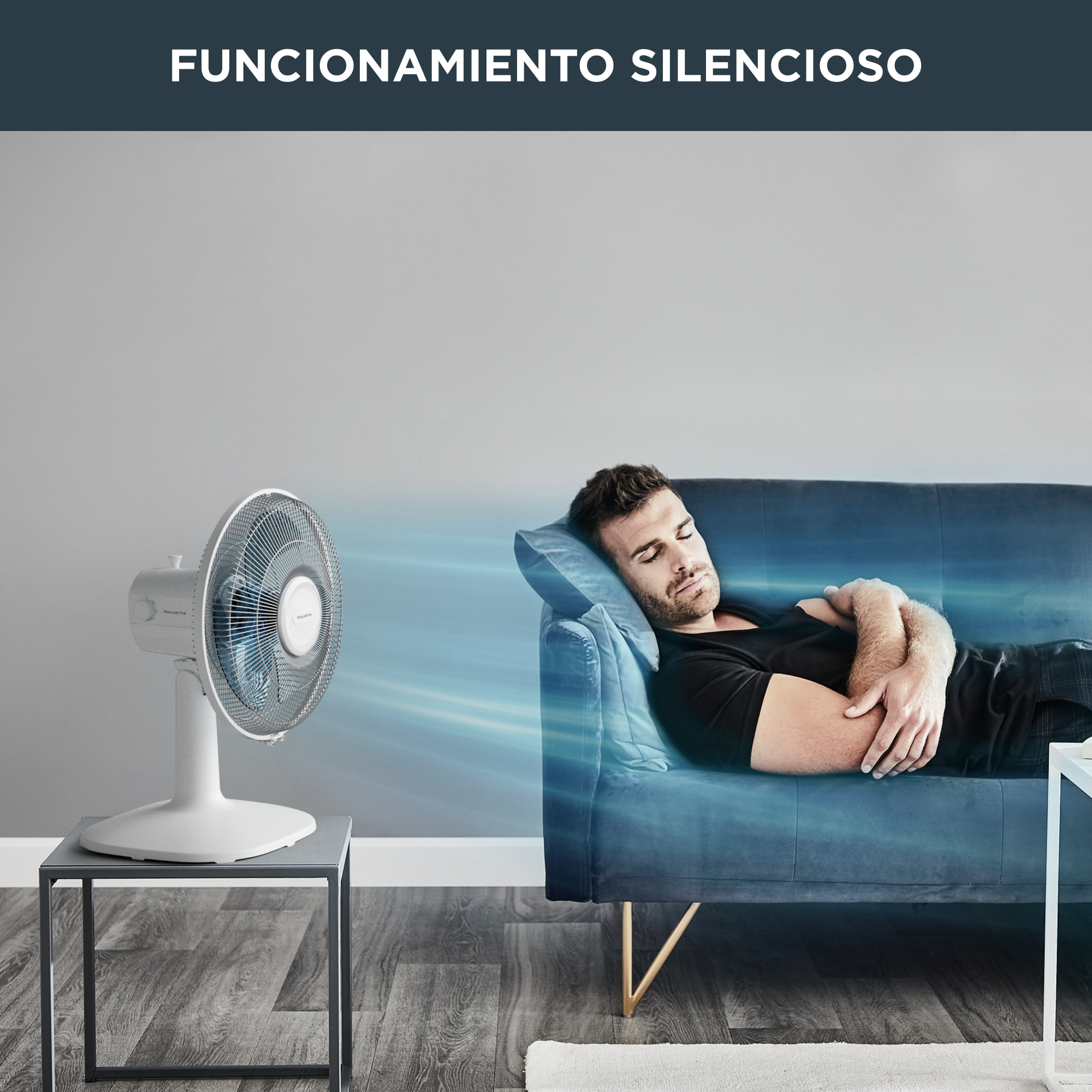 Un hombre duerme en un sofá azul. Un ventilador blanco está en una mesa. Texto: "Funcionamiento Silencioso."