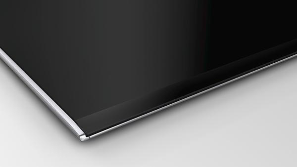 Nahaufnahme einer schwarzen, glänzenden Oberfläche mit silbernem Metallrand auf weißem Hintergrund.