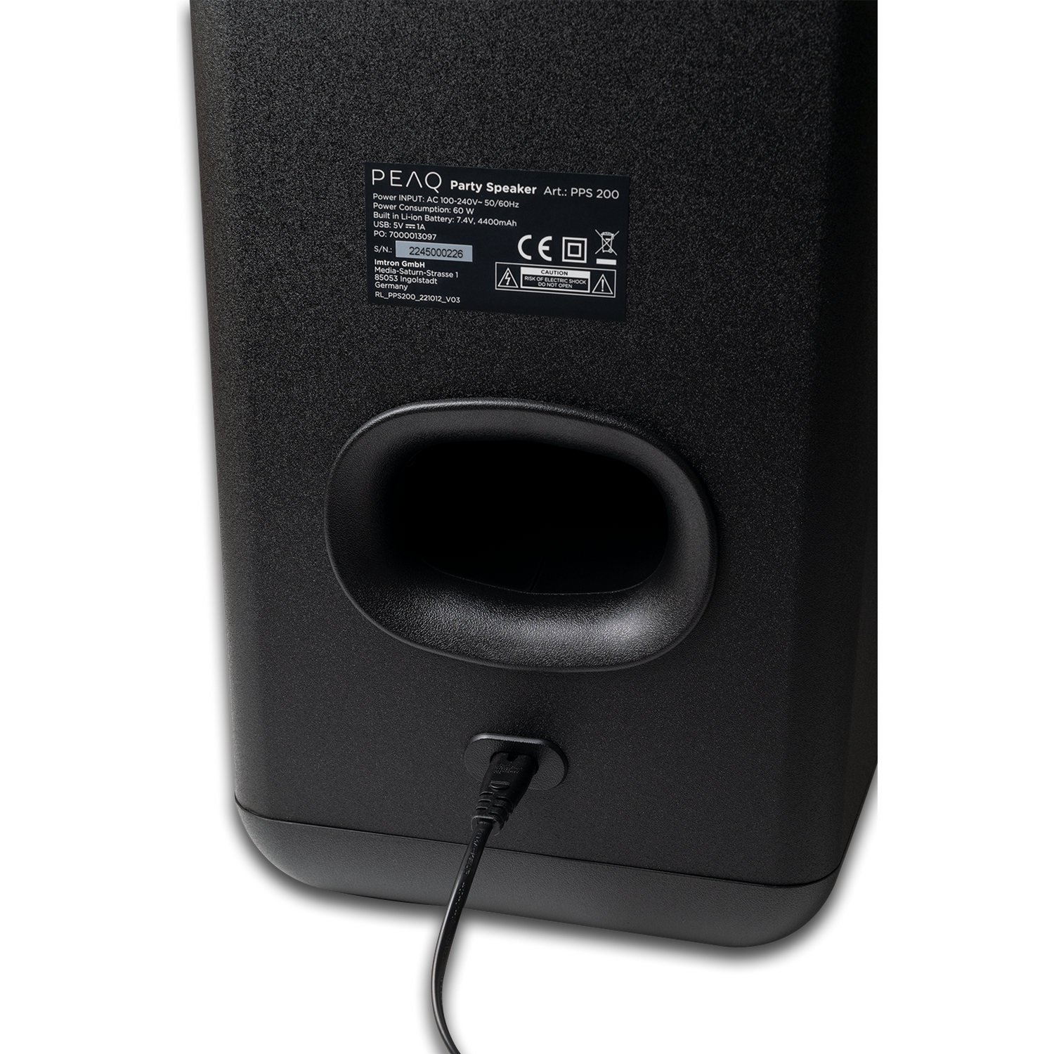 The back of a black speaker with a port for a power cord.