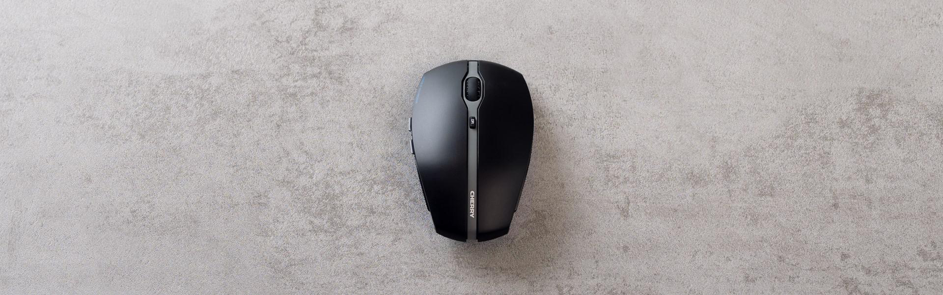 Eine schwarze Computermaus auf einer grauen Oberfläche. Die Maus hat ein glattes Design.