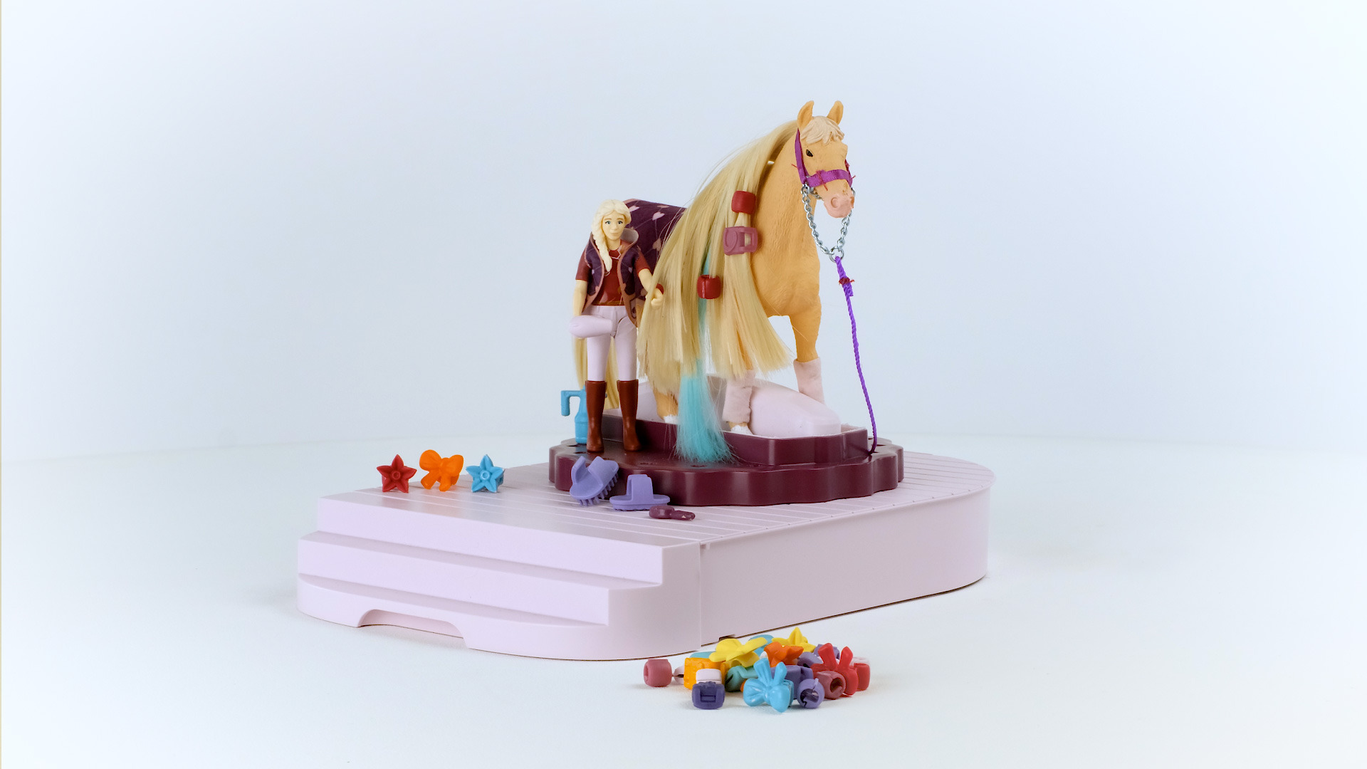 Ein Pferd und Reiter Spielzeug-Set auf einer rosa und lila Bühne mit Zubehör.