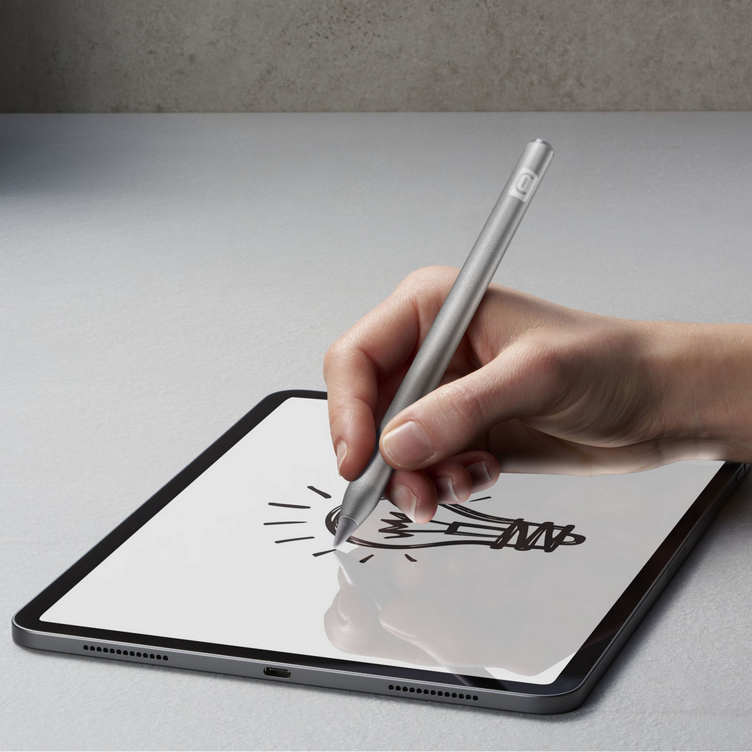 A hand holding a silver stylus pen on a tablet.