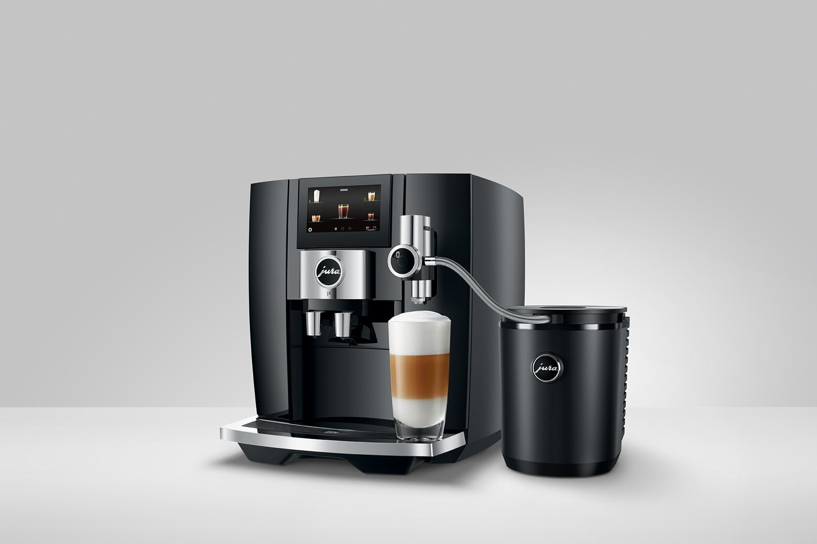 Schwarze Jura Kaffeemaschine. Glas mit Kaffee wird gefüllt. Schwarzer Milchbehälter daneben.