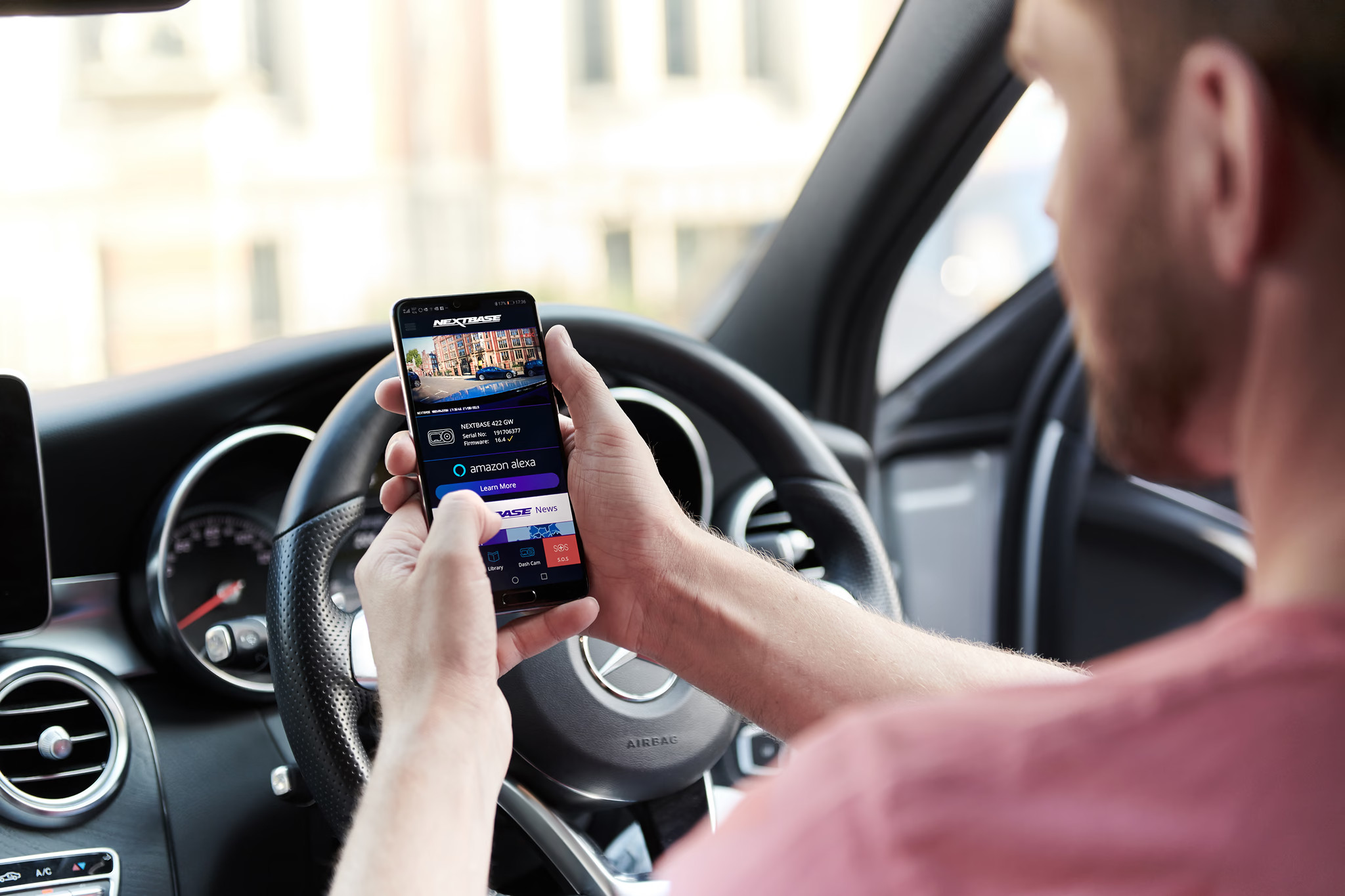 Un homme dans une voiture regardant un smartphone affichant une application.