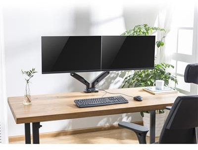 Bureau met twee monitoren. Toetsenbord, muis, plant en andere items op het bureau.