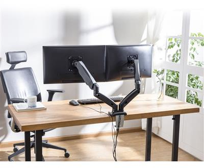 Een bureau met een monitorbevestiging, twee monitoren, een toetsenbord en een koffiemok.