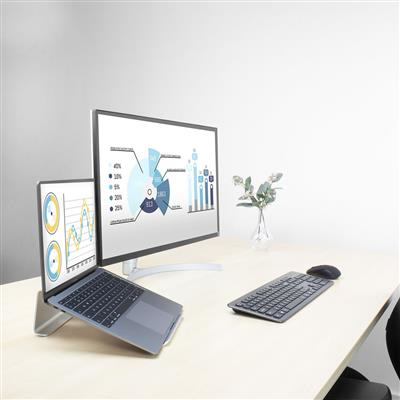 Laptop and monitor on a desk. The monitor displays a chart. The laptop is open.