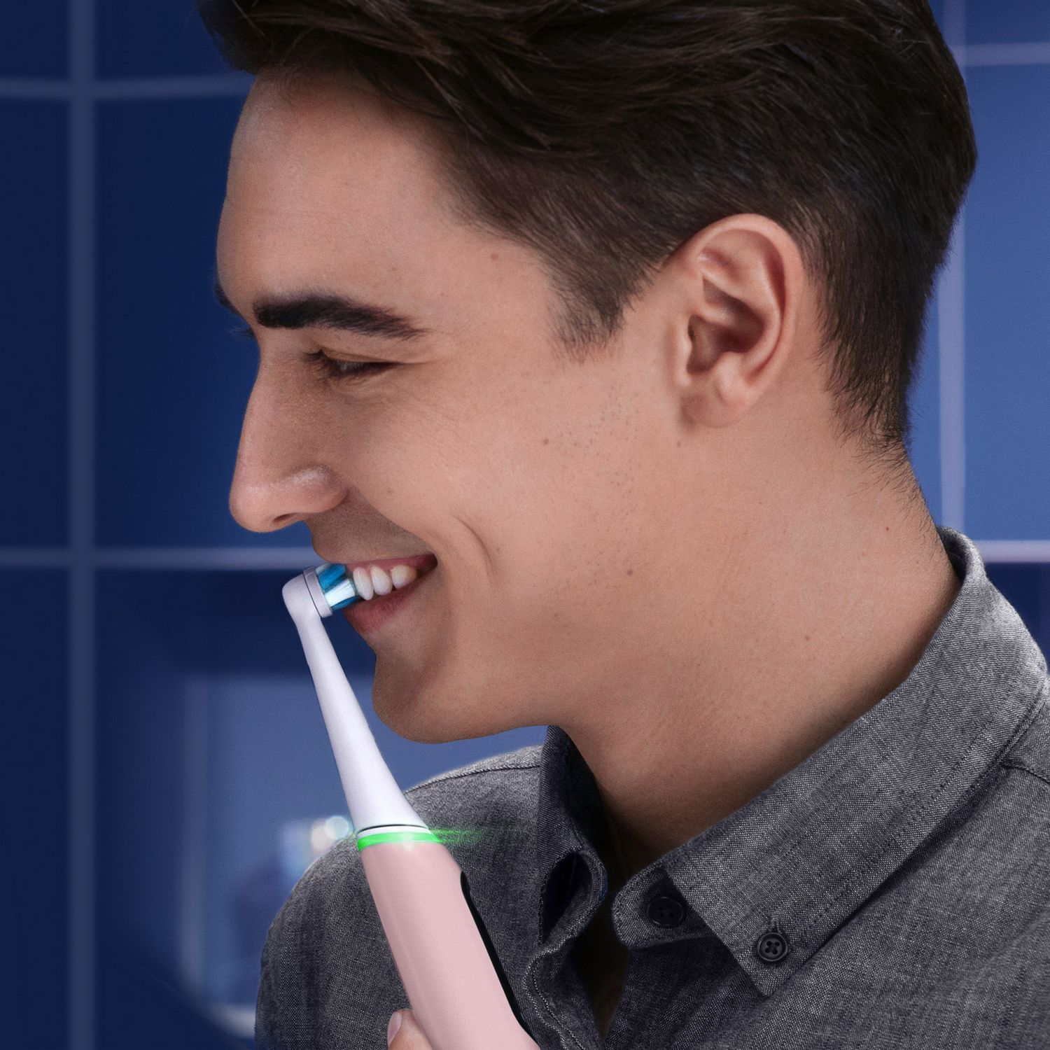 Man brushing his teeth with a pink electric toothbrush. Smiling, close-up.