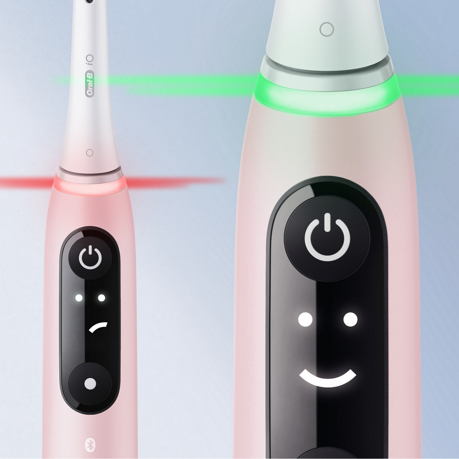 Two pink electric toothbrushes with power buttons and smiley/sad faces.