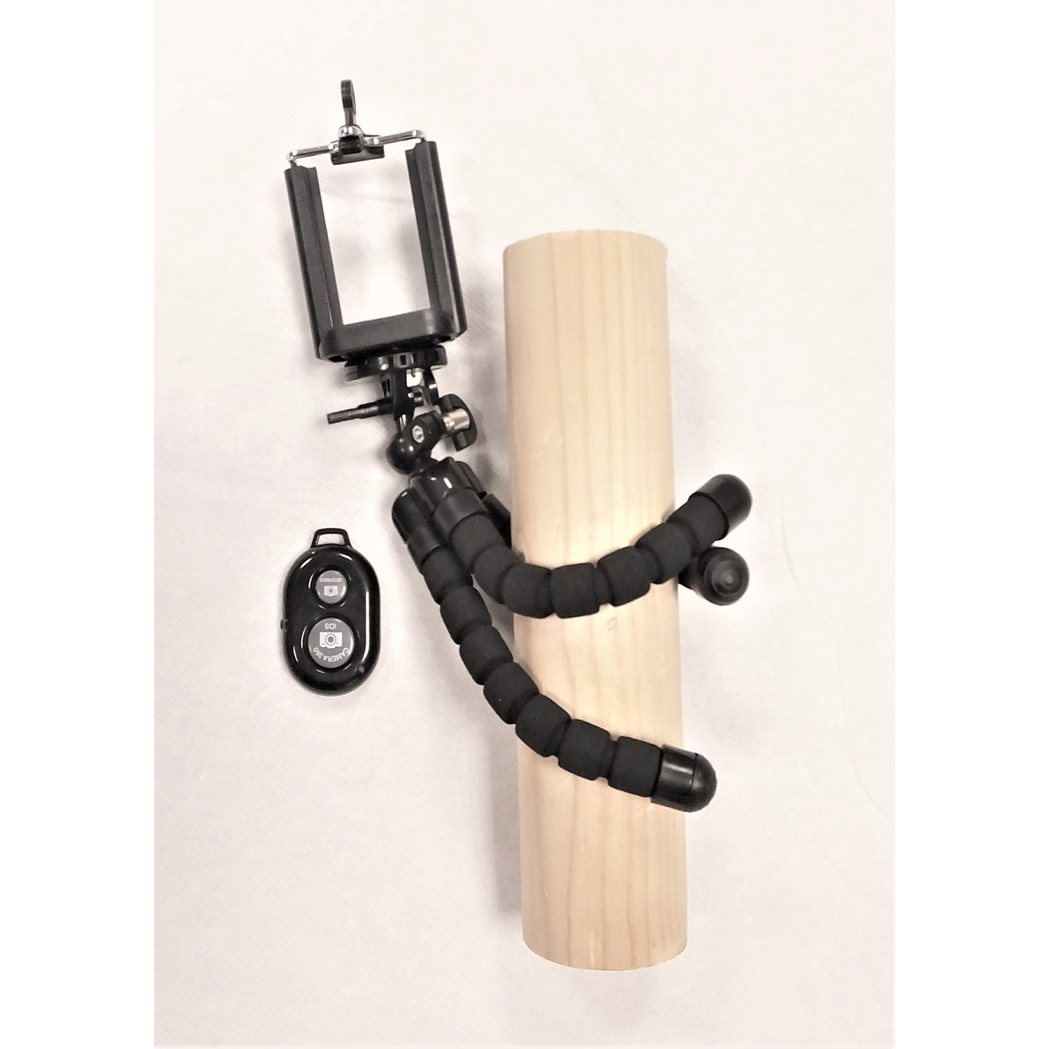 Un treppiede con supporto per telefono, un telecomando e un palo di legno.