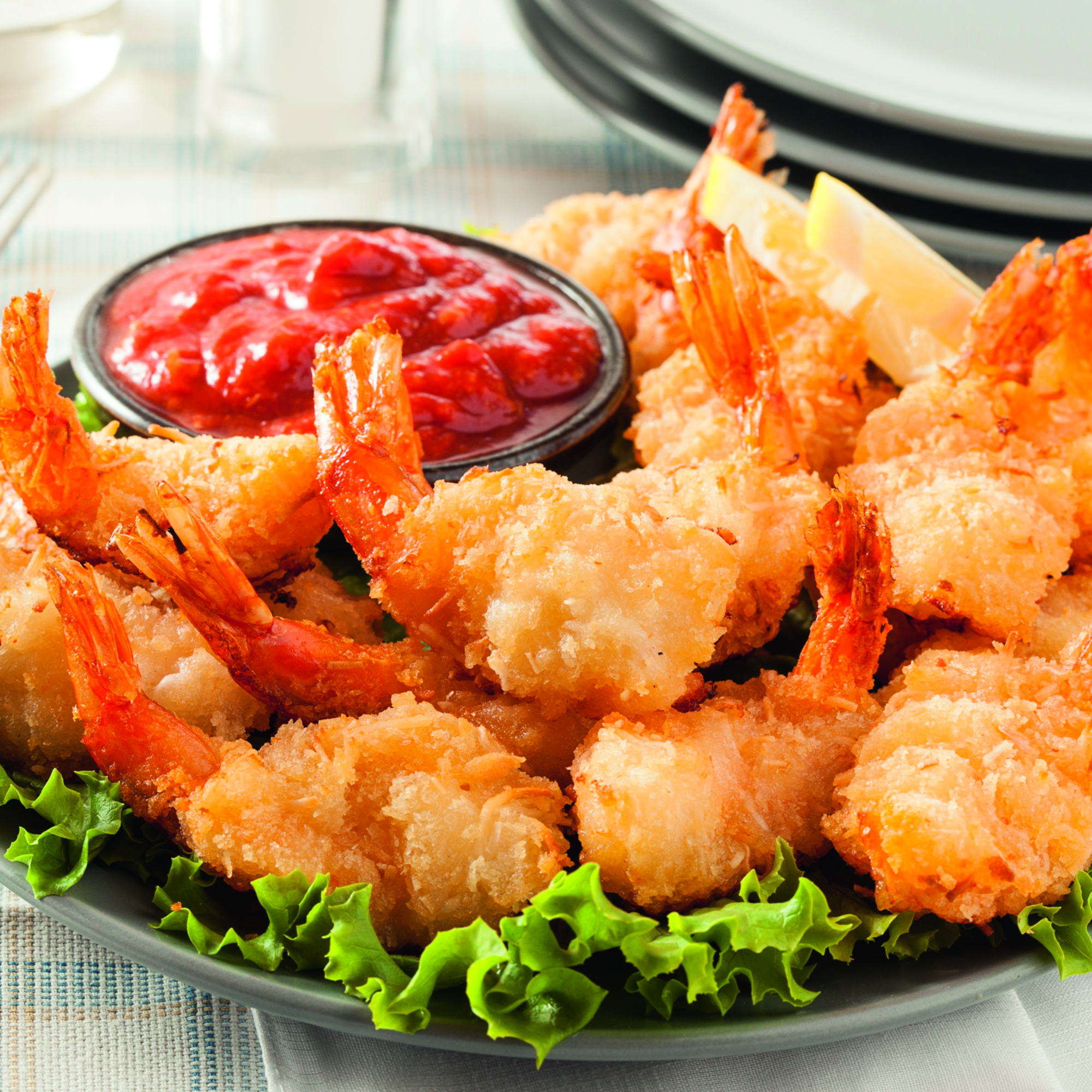 Plato de camarones fritos con salsa roja. Lechuga verde debajo.