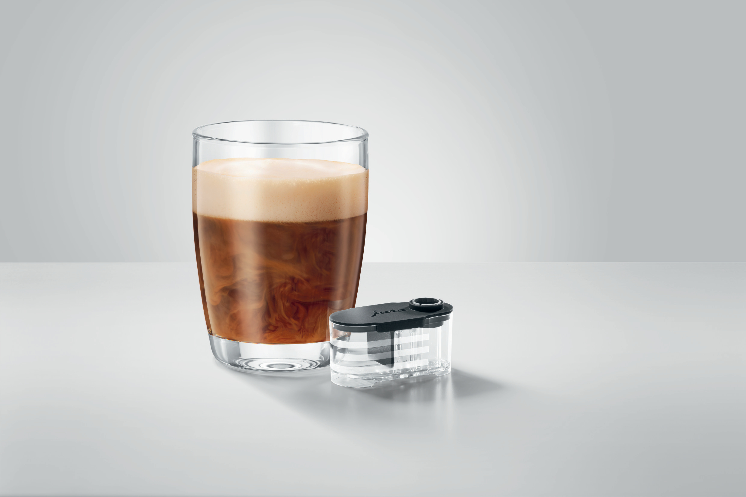 Glas Kaffeegetränk und schwarzer Jura-Filter. Weißer und grauer Hintergrund.