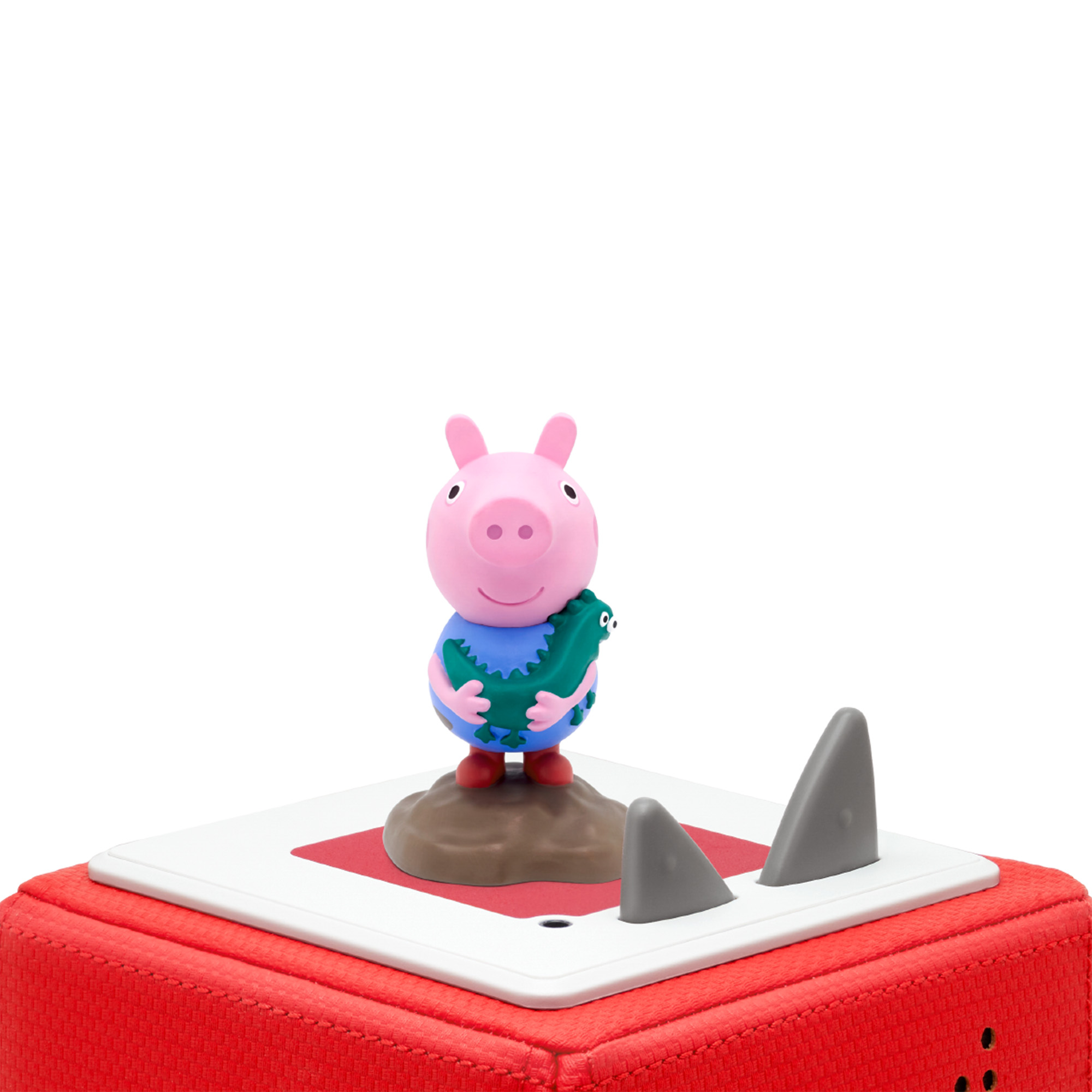 Peppa Wutz Spielfigur mit Spielzeugkrokodil auf rotem und weißem Würfel mit Hai-Flossen-Akzenten.
