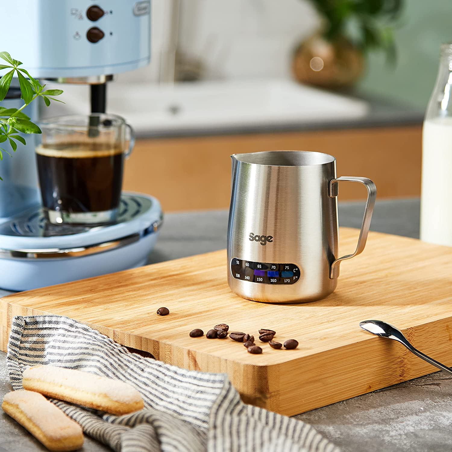 Una jarra de acero inoxidable para espumar leche con granos de café.