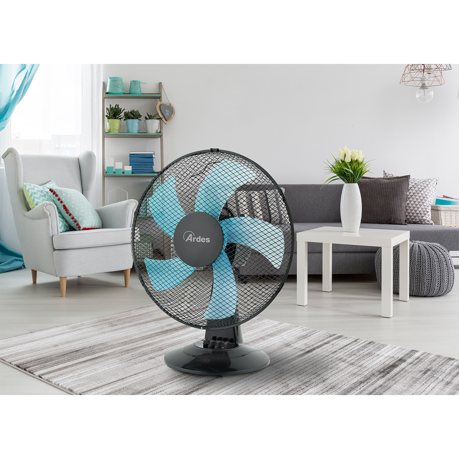 Un ventilatore nero e blu su un tappeto, con un soggiorno sullo sfondo e un tavolo bianco.