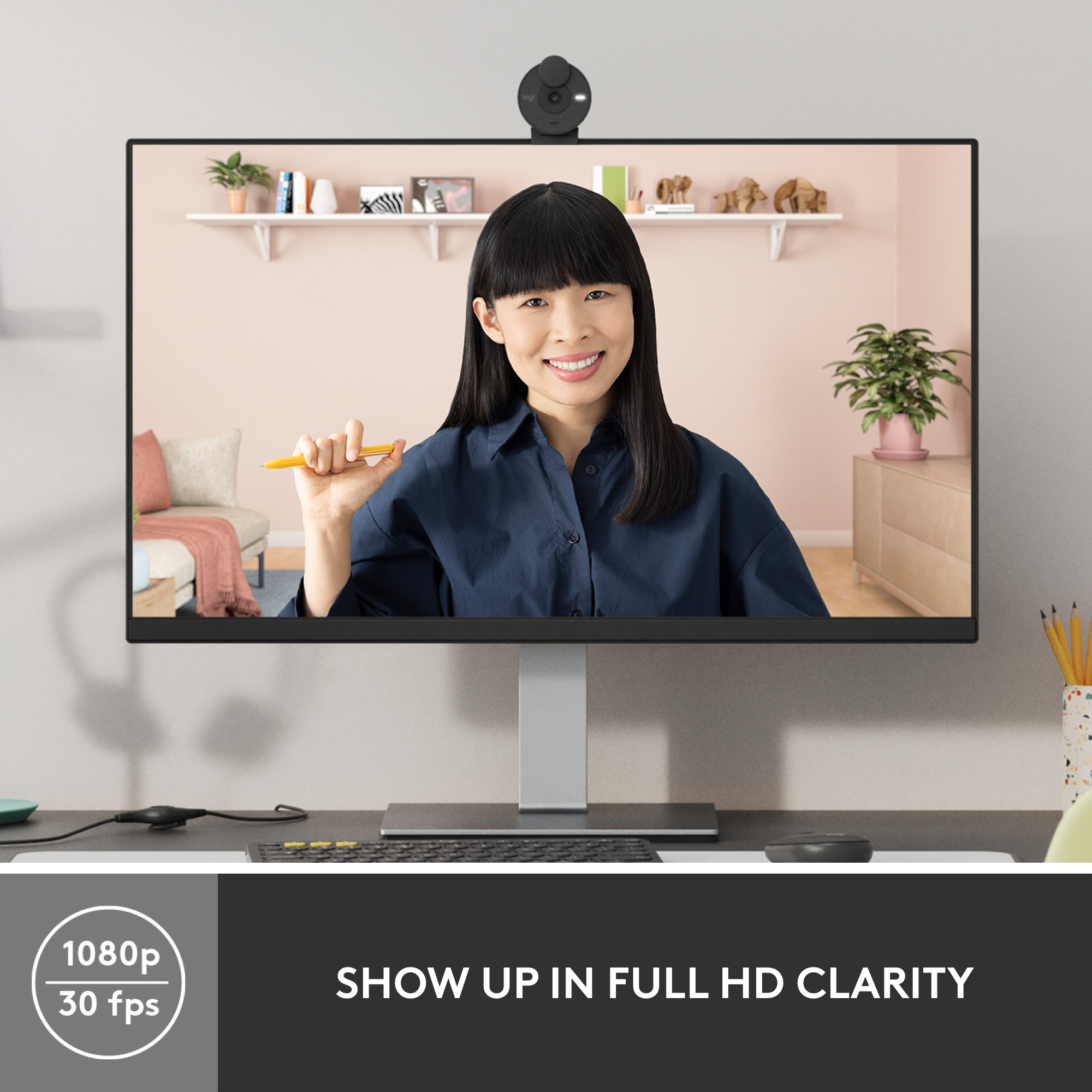 Une femme est sur l'écran d'un moniteur. Une webcam est au-dessus du moniteur. Un clavier et une souris sont devant le moniteur.