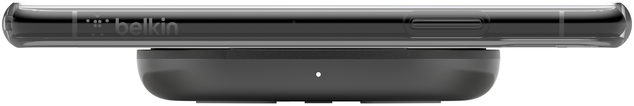 Un chargeur sans fil noir avec un téléphone dessus, vue latérale, sur fond blanc.