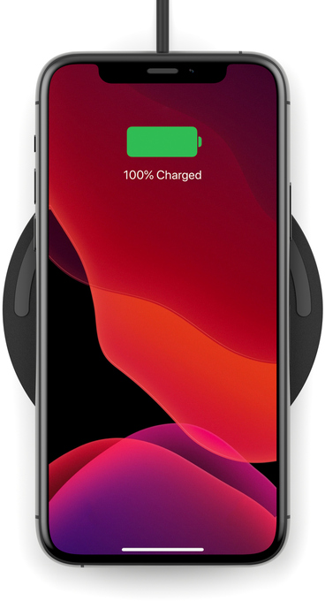 Un smartphone, se chargeant sur un chargeur sans fil noir, affiche une charge complète à l'écran.