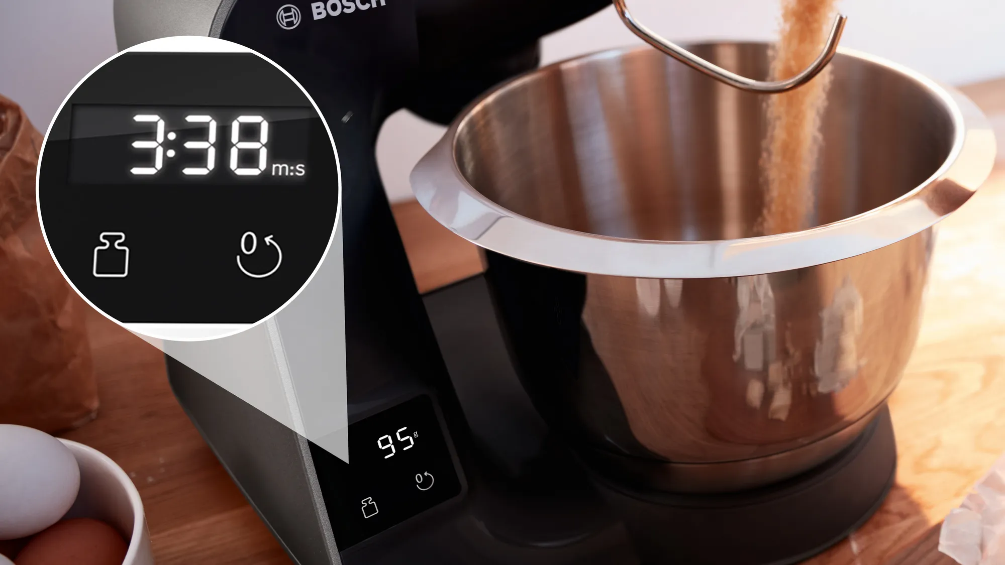 Egy konyhai mixer közelképe 3:38-at mutató digitális kijelzővel, súly és időzítő gombbal, és egy tál.