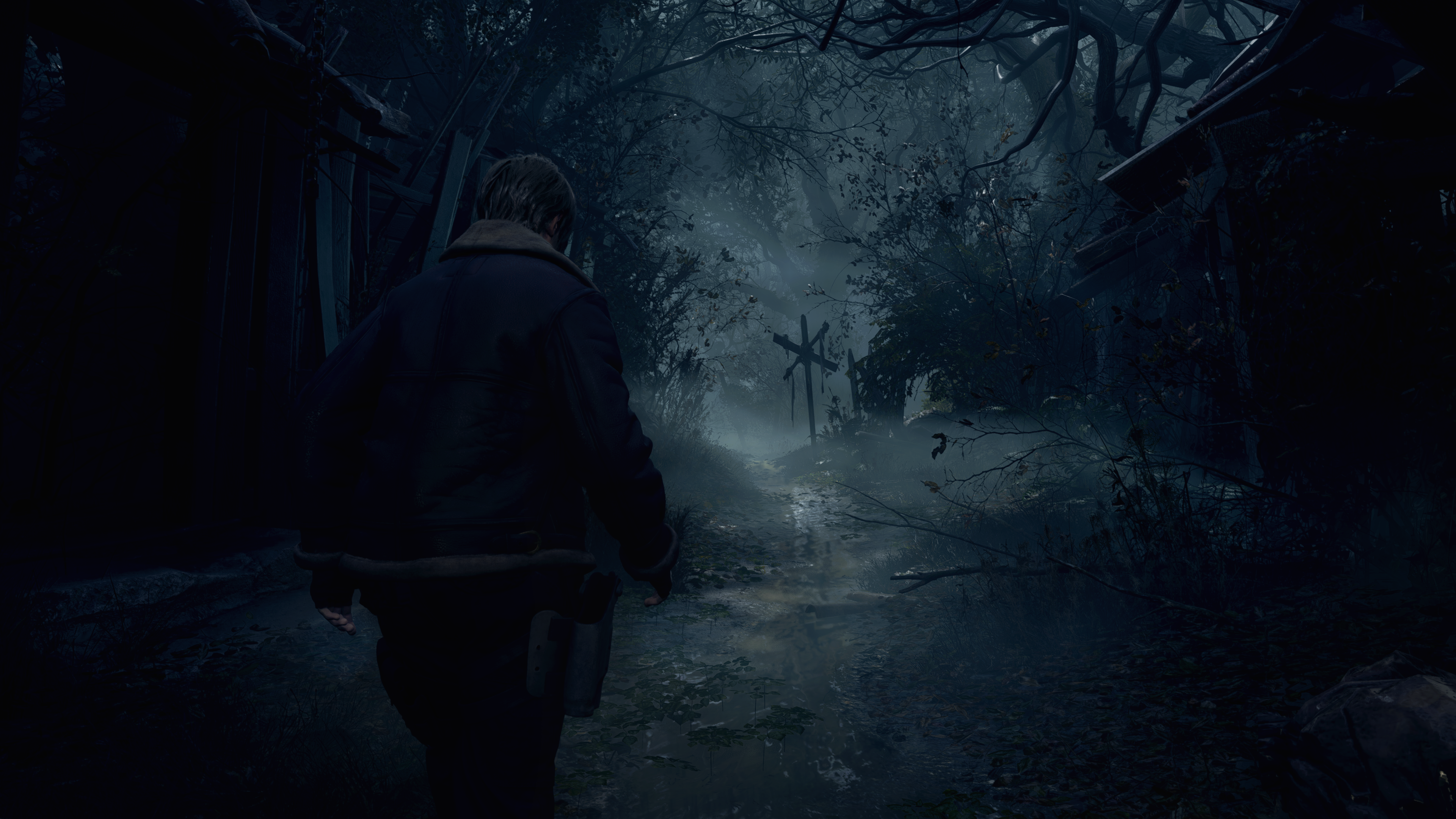 Un hombre camina por un bosque oscuro y brumoso. Se aleja de la cámara. La escena es oscura.