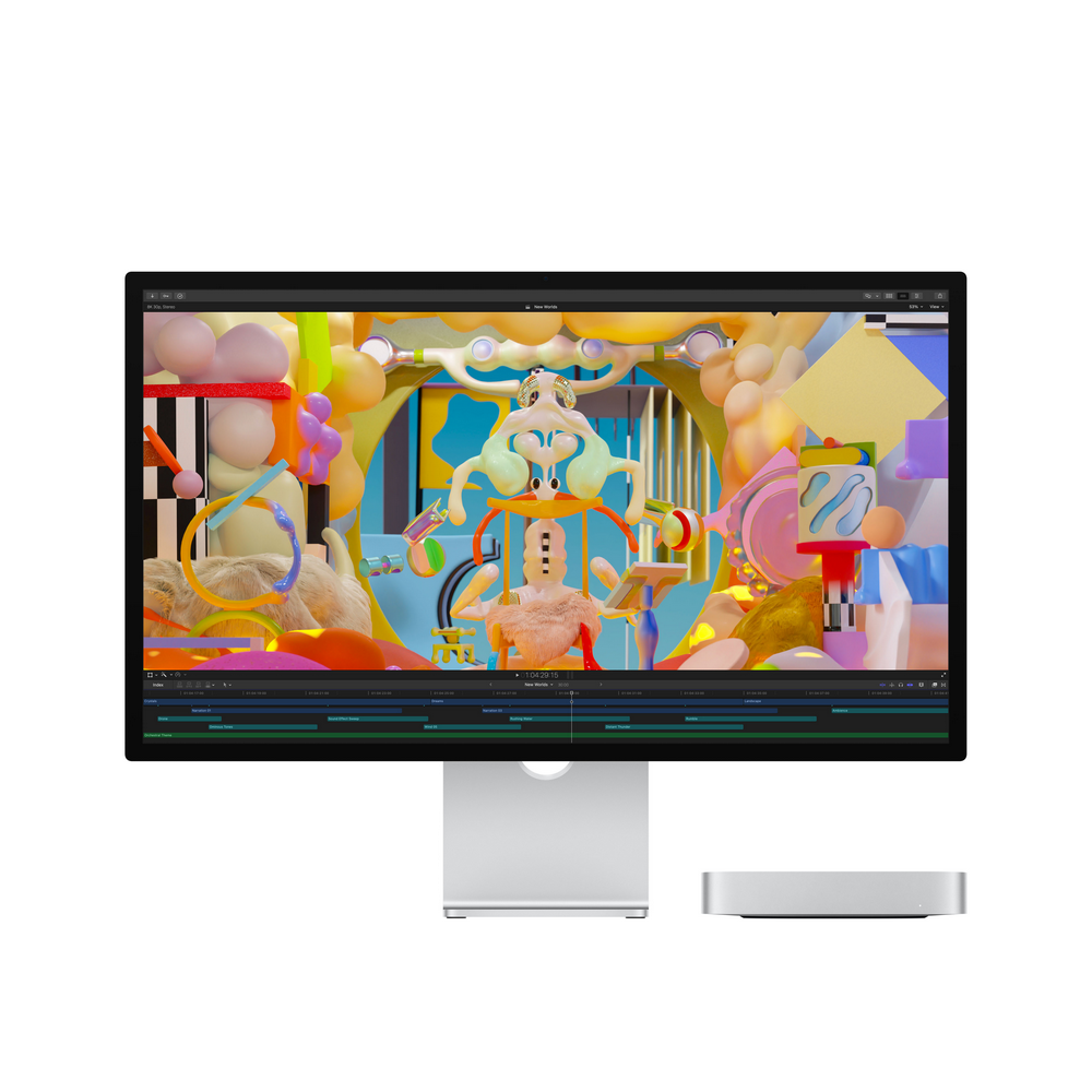 Un monitor de computadora con una escena de dibujos animados colorida, con un soporte plateado y una mini computadora plateada.