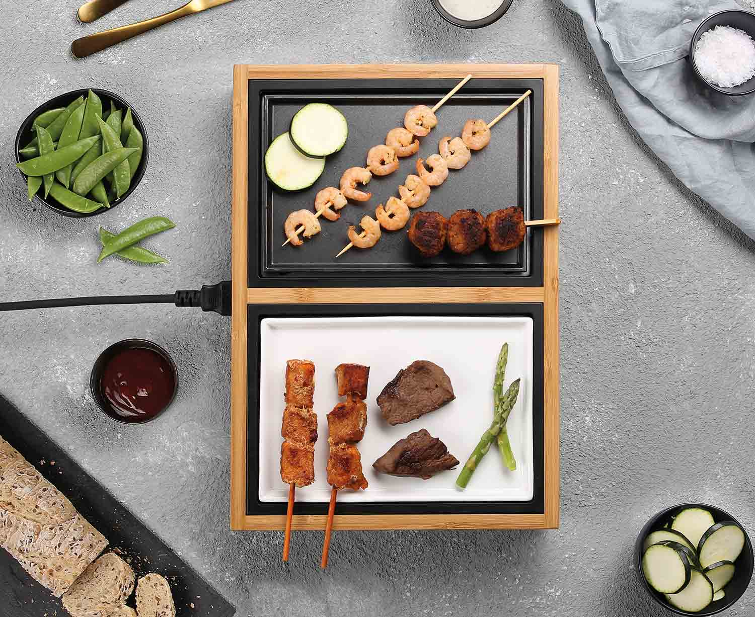 Un grill avec des brochettes de crevettes et de viande, des courgettes et d'autres aliments.