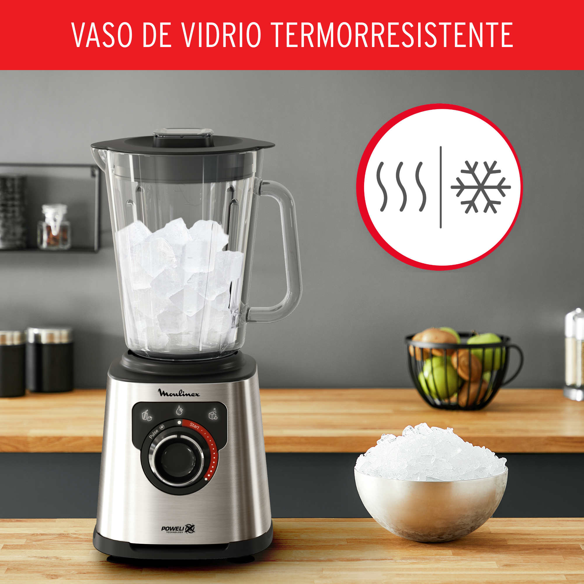 Licuadora con hielo y un cuenco de hielo sobre una encimera de madera. En el fondo, un cuenco de manzanas.