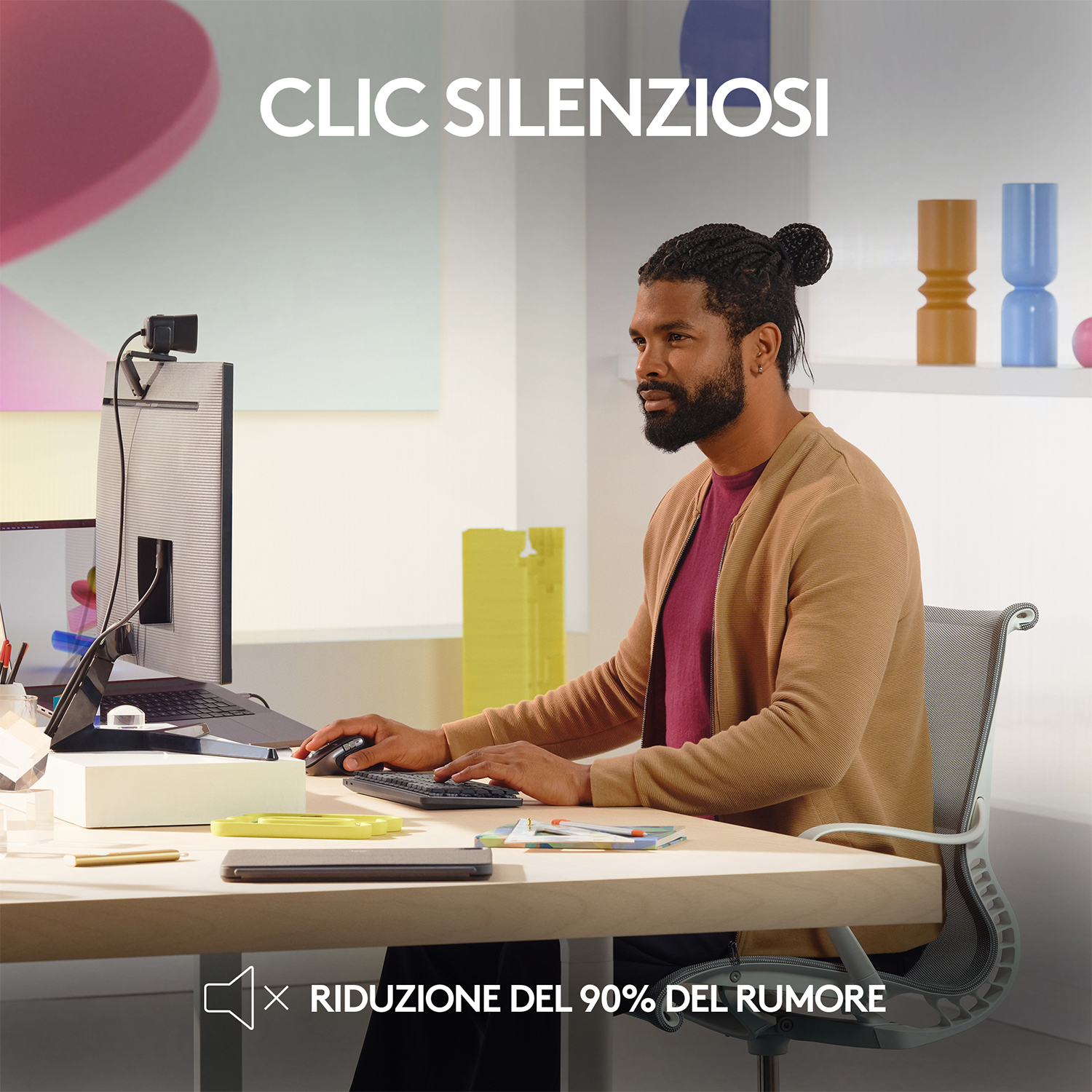 Un uomo è seduto a una scrivania, che usa un computer e un monitor.