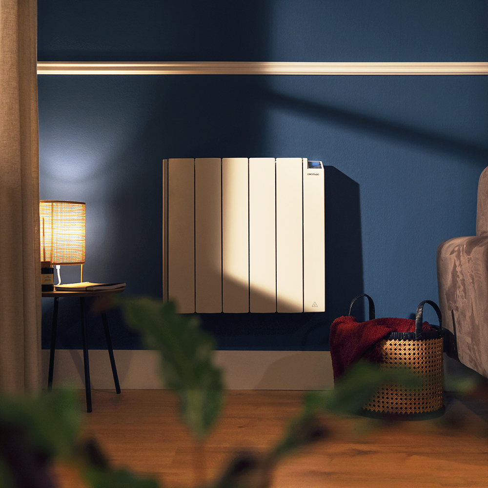 Calentador beige en pared azul. Lámpara y mesita a la izquierda. Cesta con manta roja a la derecha.