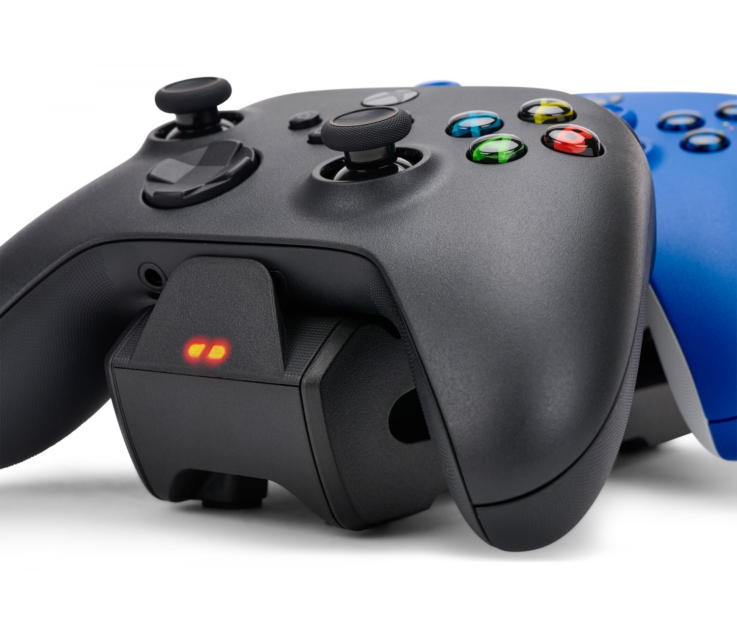 Zwei Gamecontroller, einer schwarz und einer blau, mit einer Ladestation dazwischen.