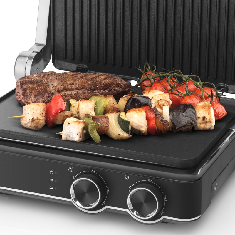 Grill steakkel, kebabbal és paradicsommal. Fekete grill és felület fekete és ezüst díszítéssel.